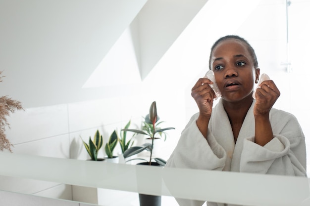 Woman using rose quartz gua sha stones to massage her face