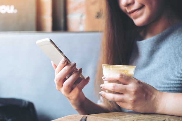 Woman using smart phone and holding coffee cup