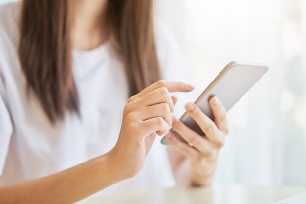 Woman using smartphone for the application on table in room.