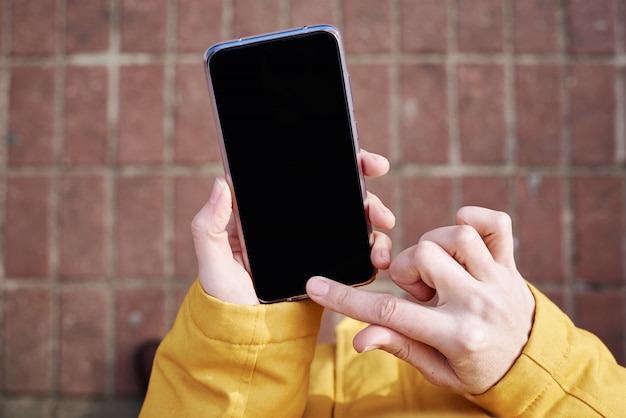 Woman using smartphone in the city outdoor, close up. Female hands typing message on mobile phone