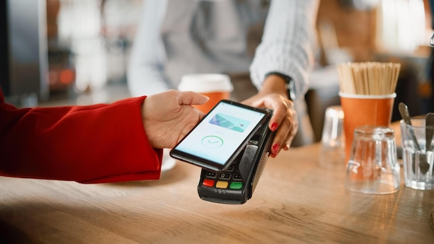 Photo a woman using a smartphone to pay for a credit card.