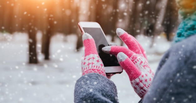 Photo woman using smartphone in winter with gloves for touch screens