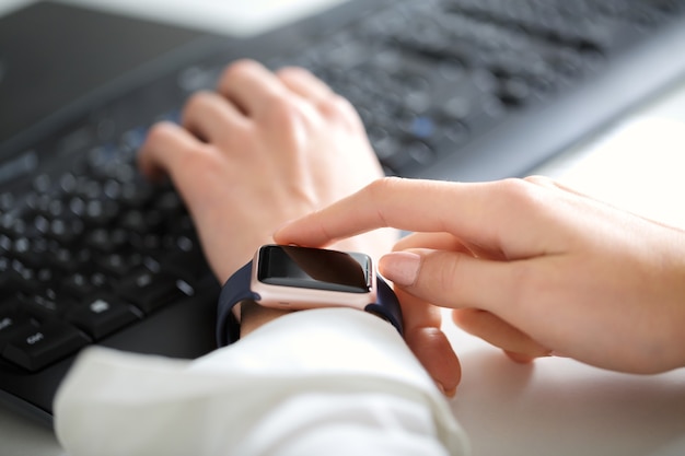 Woman using  smartwatch and working on  keyboard  in  office