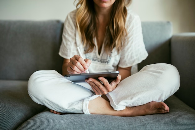 Woman using a stylus writing on a digital tablet  during coronavirus quarantine