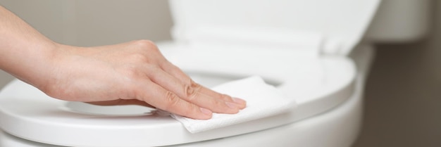 Woman using tissue paper clean the toilet in the bathroom at home