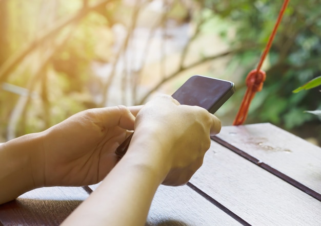 Woman using touch screen mobile phone with Coffee shop blur background