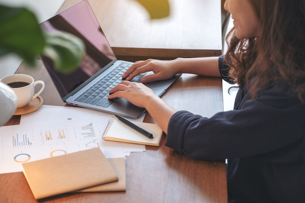 woman using and typing on laptop while working in office