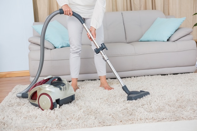 Woman using vacuum cleaner on rug