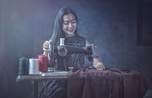 Woman using vintage sewing machine. adorable elderly woman sewing clothes