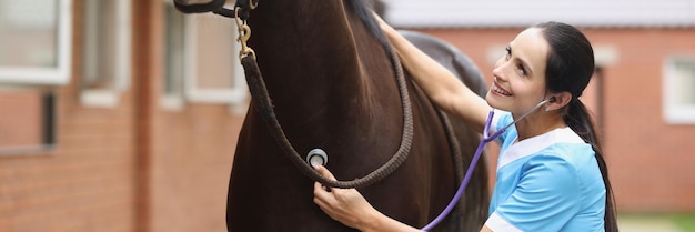 Woman veterinarian listens to horse heartbeat with stethoscope heart problems in sport horses