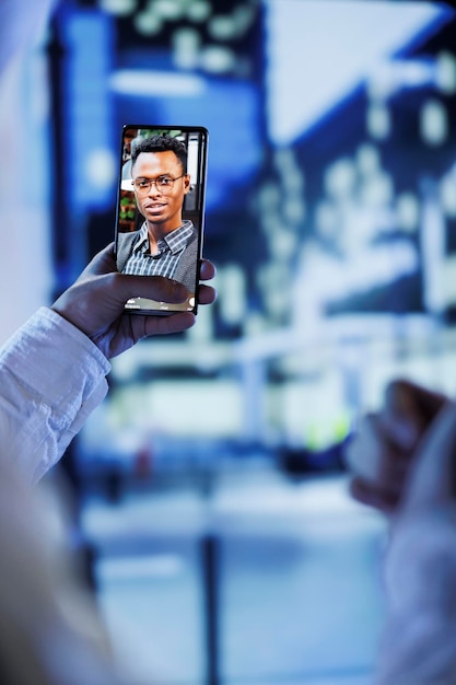 Woman in videocall with husband while walking around city streets at night close up Citizen using smartphone to show spouse surroundings in dimly illuminated urban center in blurry background