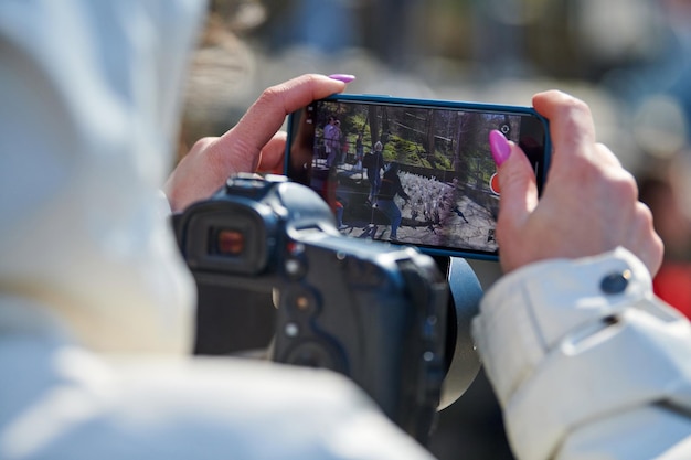 Woman videographer filming on DSLR camera and smartphone outdoor event video photo blogging