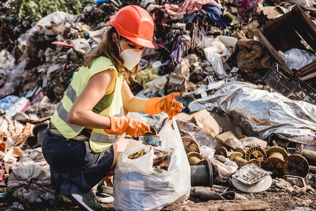 Woman volunteer helps clean the field of plastic garbage. Earth day and ecology.