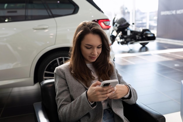 Woman waiting to buy a new car in a car dealership at the reception