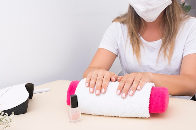 Woman waiting to do her manicure at the salon while wearing a medical mask