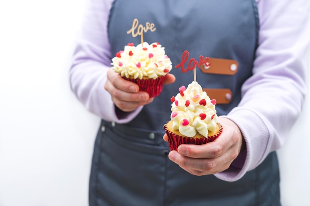 Woman waitress with two cupcakes decorated with red hearts topping and wooden sign with LOVE letters Valentine39s Day White background