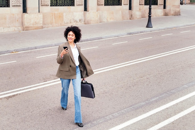 Woman walking across the street checking the phone