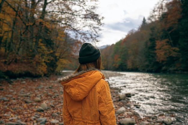 Woman walking along the river fallen leaves autumn travel