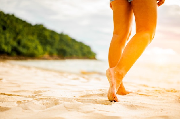 Woman walking on the beach at sunset.