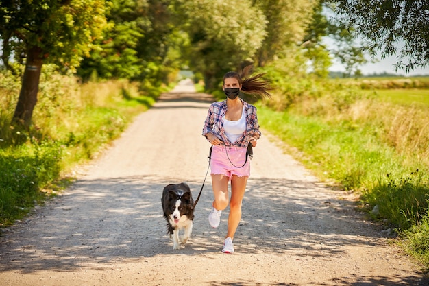 woman walking a dog in countryside and wearing a mask