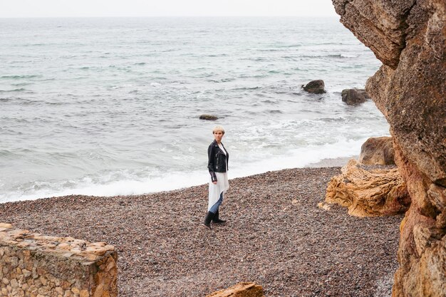 Woman walking near the cliff near sea in autumn or summer time