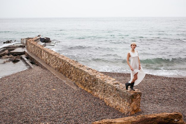 Woman walking near sea Female model with short hair having walk on cloudy day Nature spare time concept