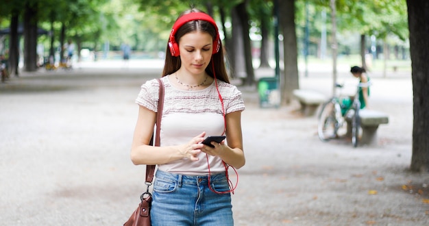 Woman walking in a park while using her smartphone to listen music