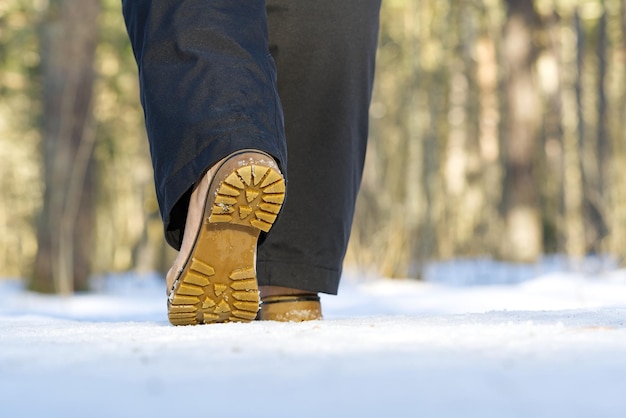 Woman walking on snow in winter forest focus on sole of show with snow