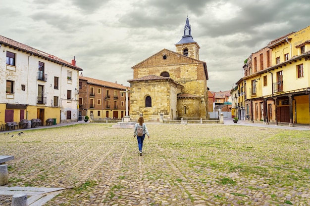 Woman walking through the old Plaza del Grano with its medieval church in Leon Spain