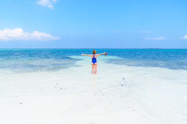 Woman walking on tropical beach. Rear view white sand