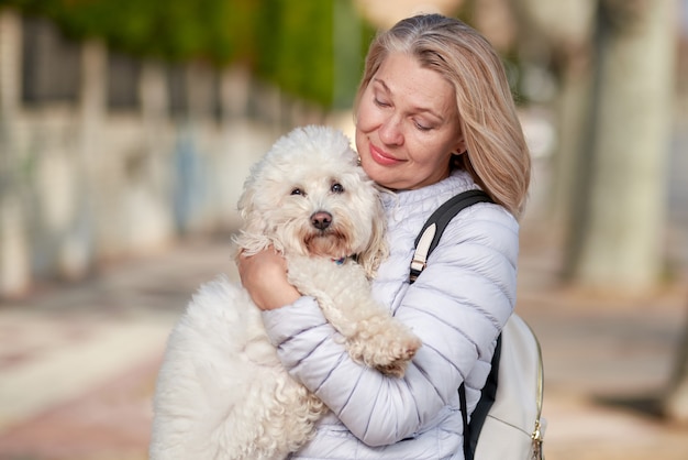 Woman walking with fluffy white dog in summer city