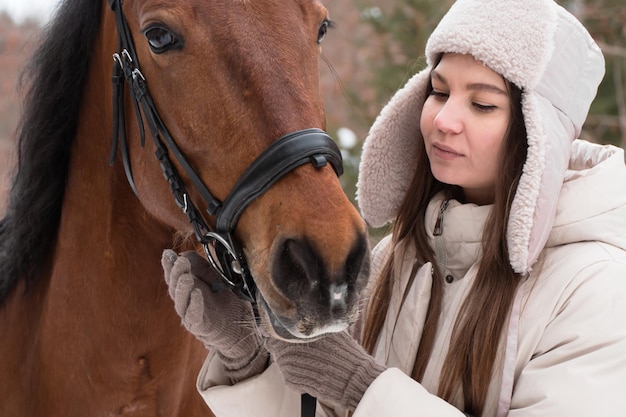 Woman walking with horse in winter day in forest.