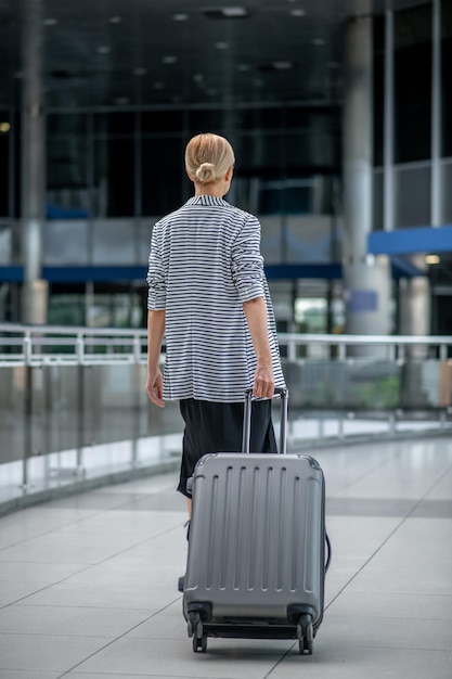 Woman walking with suitcase with back to camera