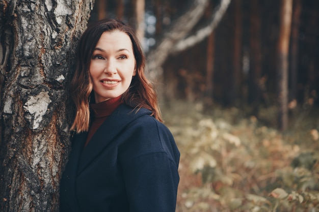 woman walking in the woods. she leaned against a tree. autumn park. The concept of walking in the fresh air