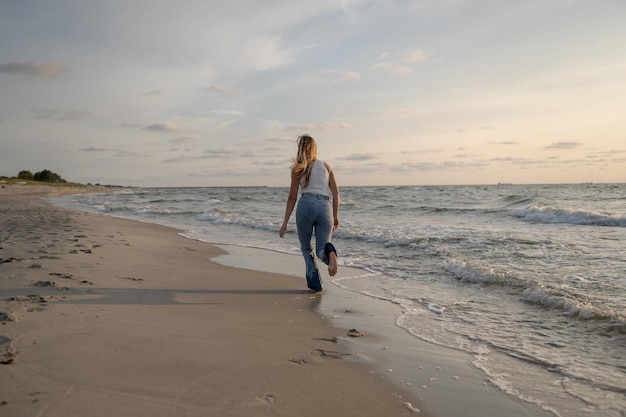 Photo a woman walks along the beach in front of the ocean