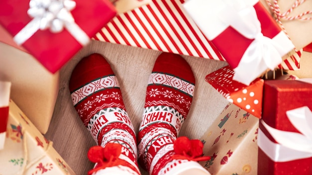 Woman in warm and comfortable red socks relaxes indoors Christmas boxes gifts