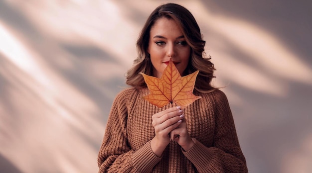 Photo woman in warm sweater holding autumn leaf