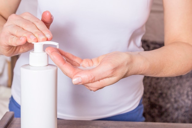 Woman washing hands with sanitizer soap disinfectant gel from plastic bottle.