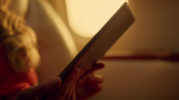 Woman watching green tablet screen on airplane trip Hands holding pad closeup