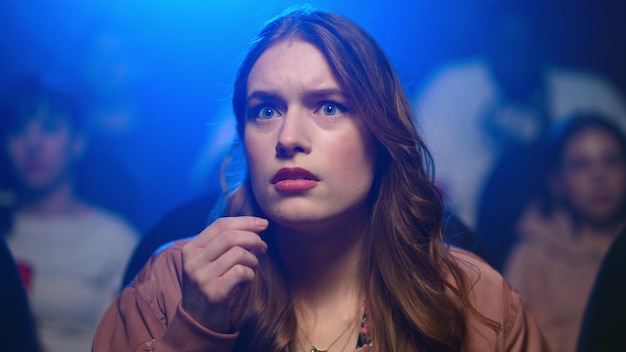 Woman watching horror in movie theatre shocked girl jumping at seat in cinema