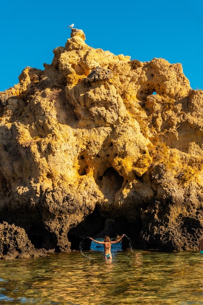 A woman in the water next to the rocks at Praia dos Arrifes Algarve beach Albufeira Portugal