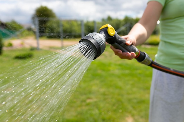 Woman watering the lawn with a garden hose with a watering can