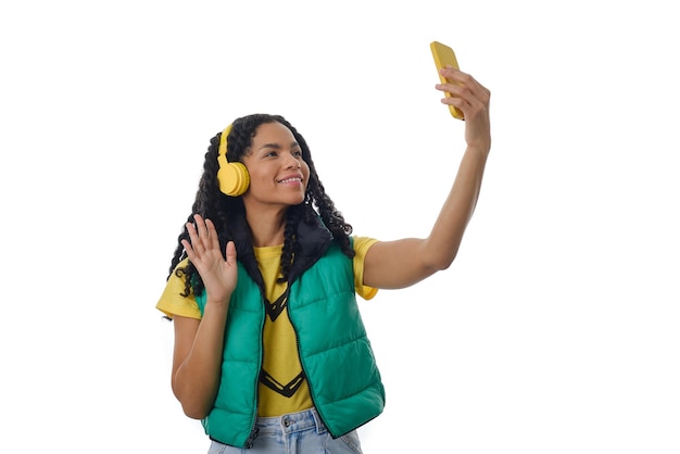 Woman waving hand greeting someone while having a video call with a mobile phone on an isolated background. Technology and communication concept.