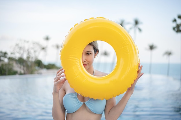 Woman wear blue swimsuit posing with yellow inflatable rubber ring.