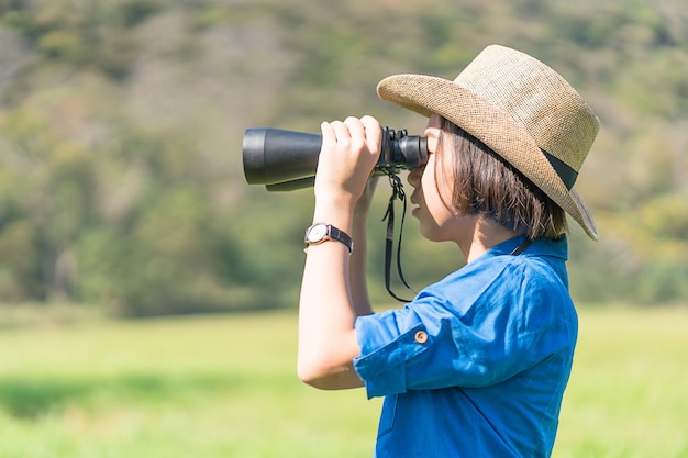 Woman wear hat and hold binocular in grass field