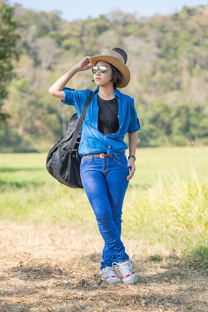 Woman wear hat walking and carry her guitar bag 