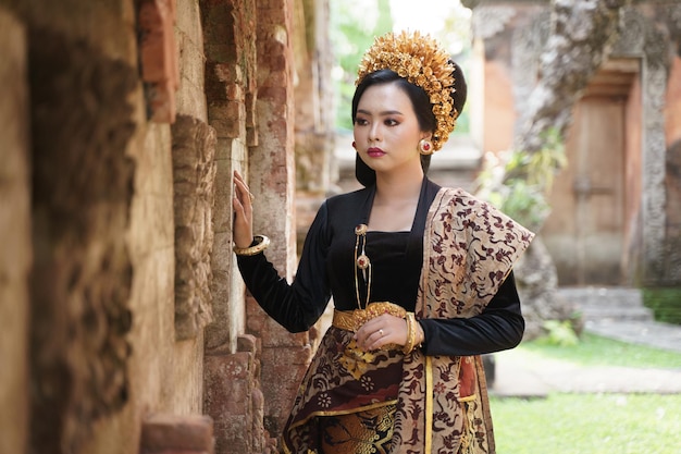 Woman wearing balinese kebaya standing near a relief fence