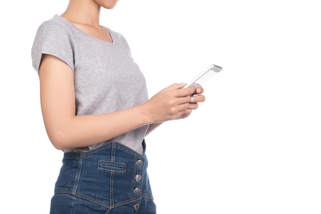 woman wearing blank gray t-shirt, jeans using mobile smartphone isolated on white background.