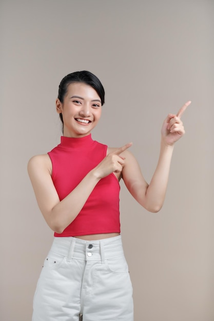 woman wearing casual clothes smiling and pointing fingers at copyspace isolated over white background