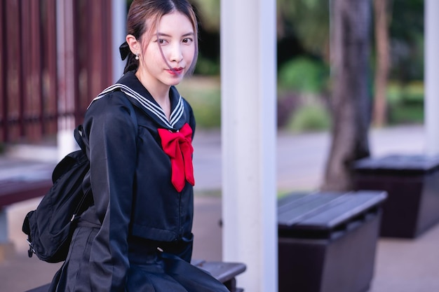 Woman wearing cosplay Japanese school uniform sitting at bus stop